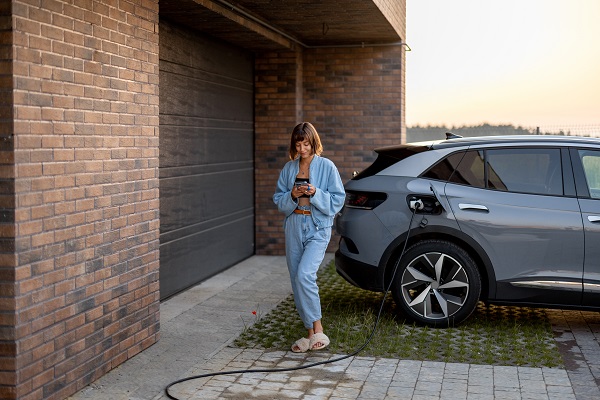 Donna ricarica la sua auto elettrica a casa.